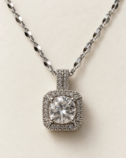 Celeste silver cushion halo pendant with a round clear centre stone on a cream background