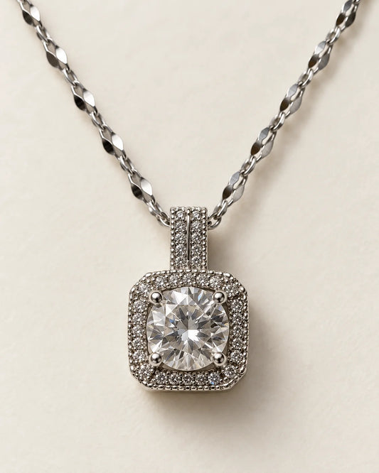 Celeste silver cushion halo pendant with a round clear centre stone on a cream background