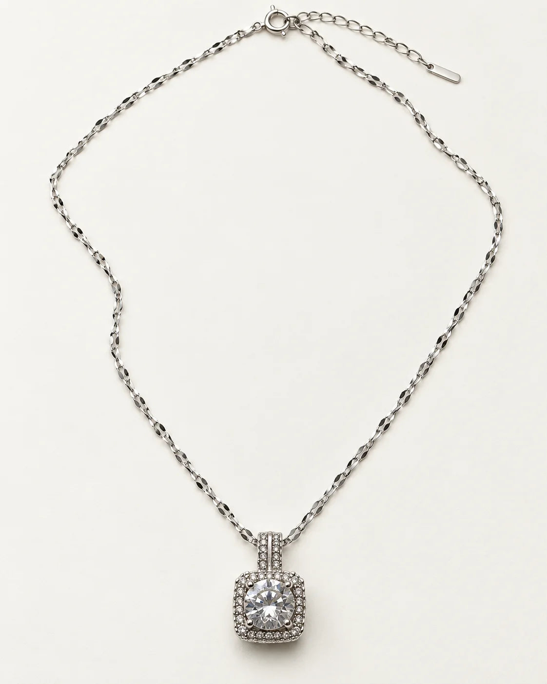 Full length of the Celeste silver cushion halo necklace laid flat with its extender chain