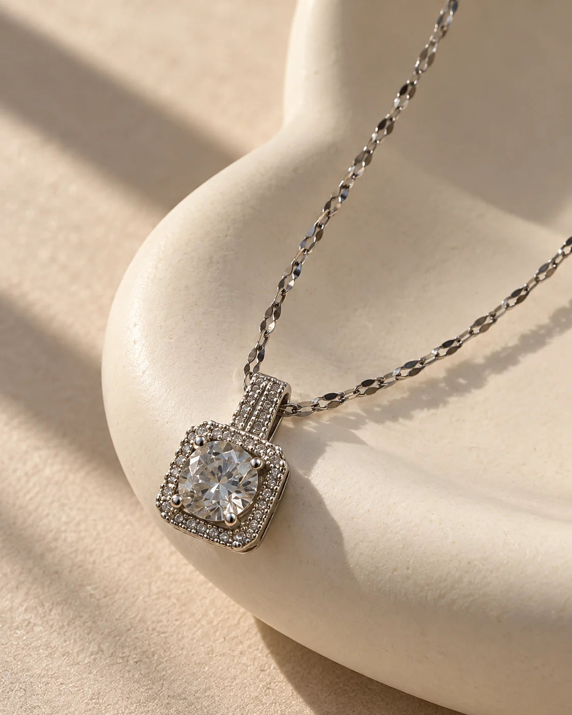 Celeste silver cushion halo pendant draped over a sculptural ivory curve