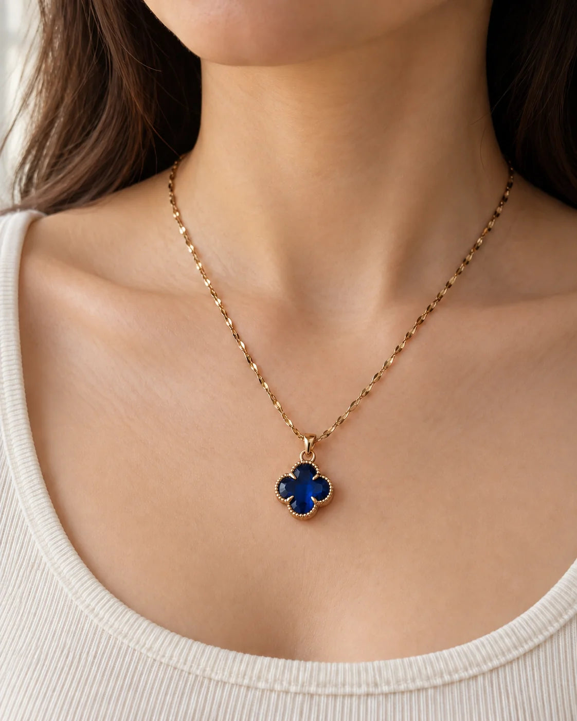 Model wearing the Fortuna sapphire blue clover necklace with an ivory scoop-neck top