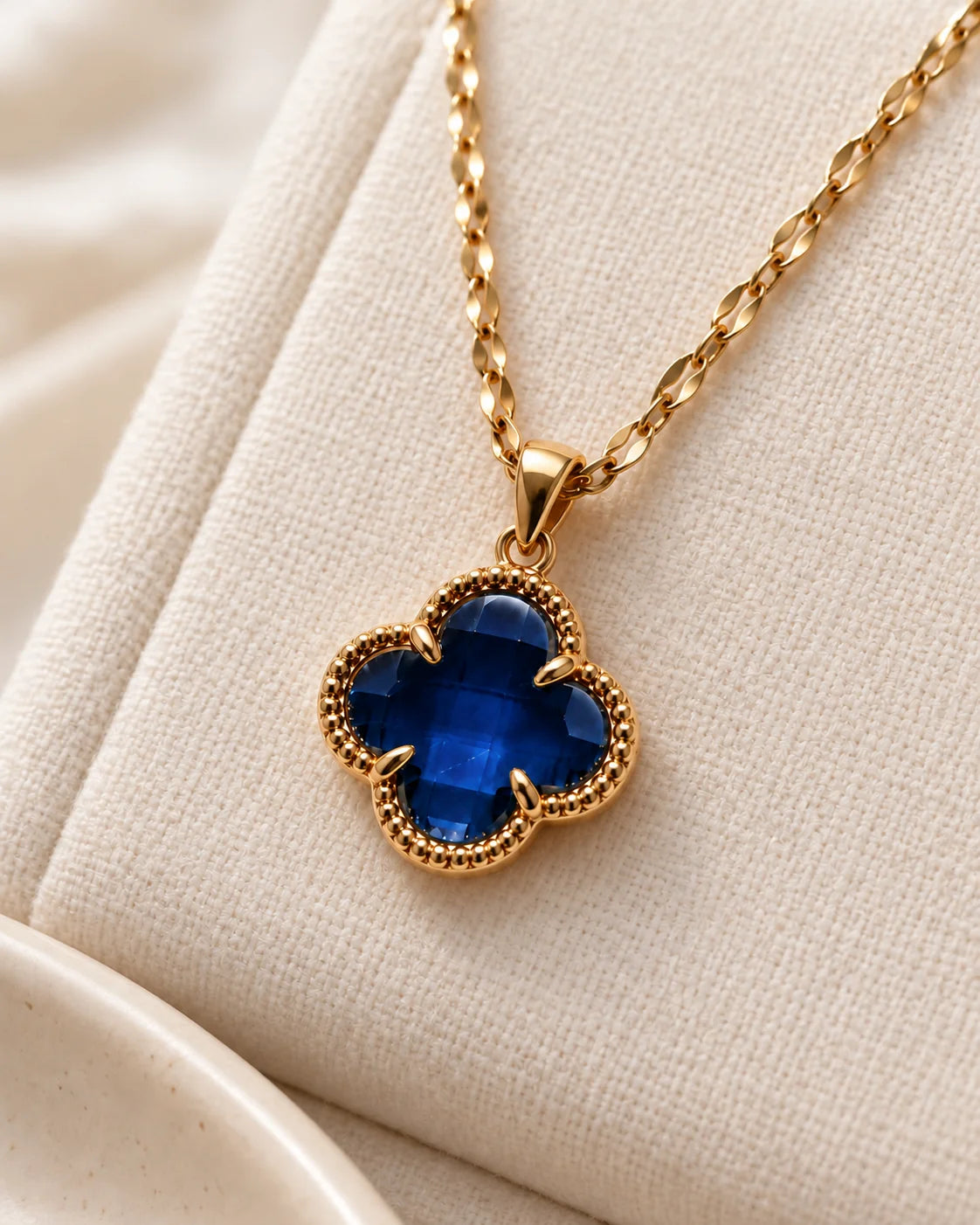 Fortuna sapphire blue clover necklace on ivory linen