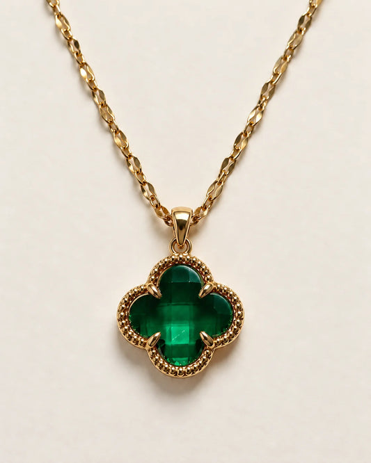 Fortuna emerald green clover pendant with a beaded gold-tone border on a cream background