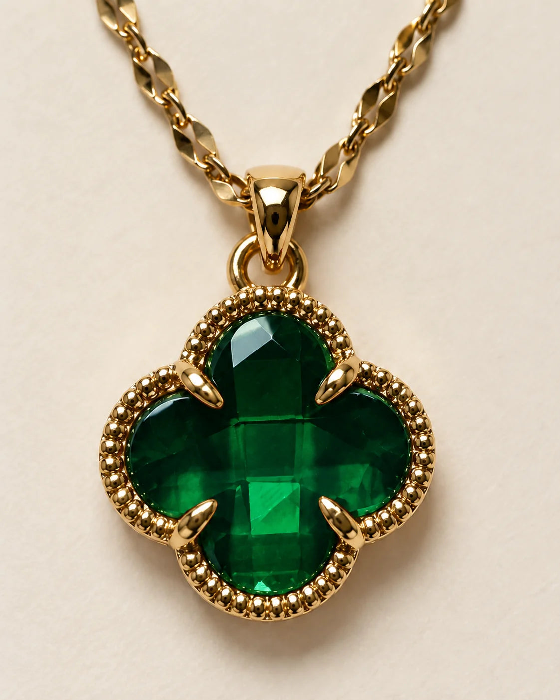 Close-up of the Fortuna emerald green clover pendant showing the faceted stone and claw setting
