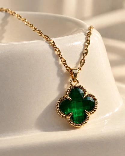 Fortuna emerald green clover pendant resting on an ivory ceramic dish