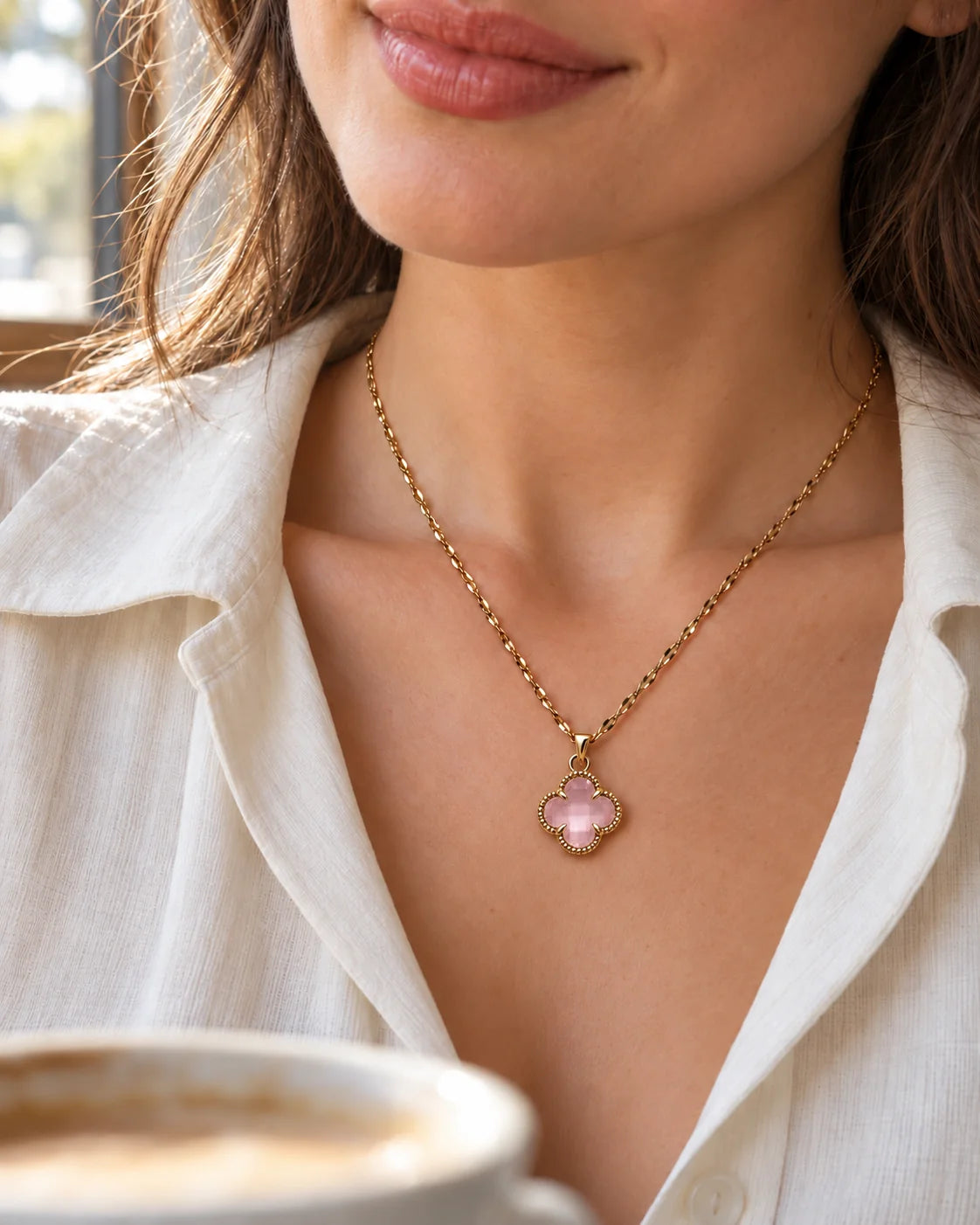 Model in an ivory blouse wearing the Fortuna baby pink clover necklace