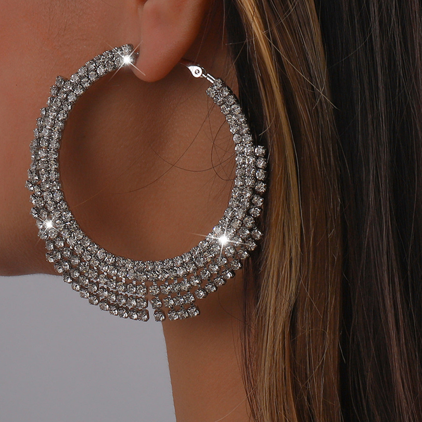 Close-up of a person wearing a large, sparkling hoop earring.