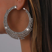 Close-up of a person wearing a large, sparkling hoop earring.