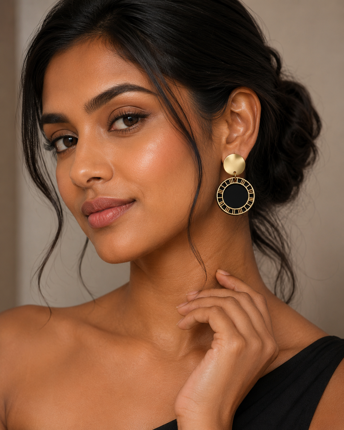 A close-up of a woman wearing a gold and black drop earring with a gold heart-shaped stud and a circular black-and-gold ring setting.