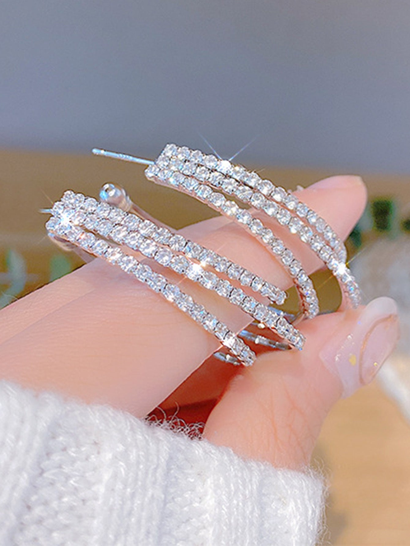 A close-up of a hand holding a Celestia Silver Crystal Circle Drop Earrings for women