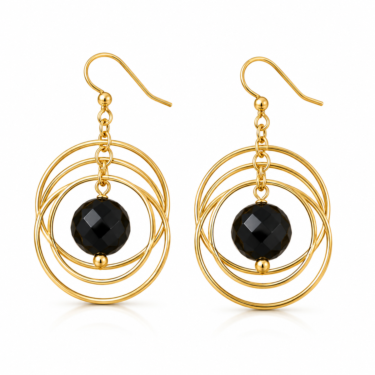 A pair of gold dangle earrings with a triple-ring circular wireframe design and a faceted black bead at the center, shown on a clean white background.