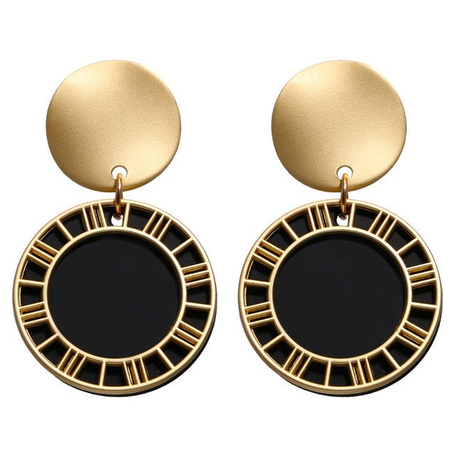Pair of gold and black earrings on a white background