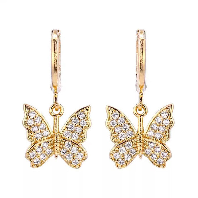A pair of gold butterfly drop earrings with pavé-set clear stones, shown on a plain white background.