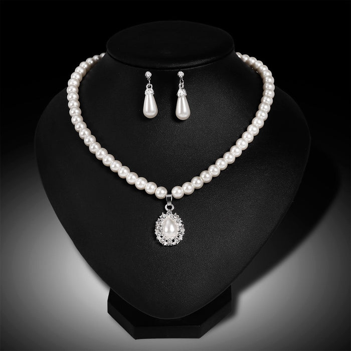 Pearl necklace and earrings set on a black stand with a dark background