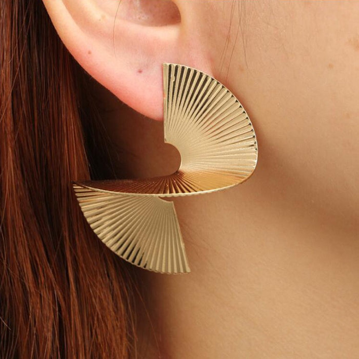 Gold earrings worn by a person with brown hair.