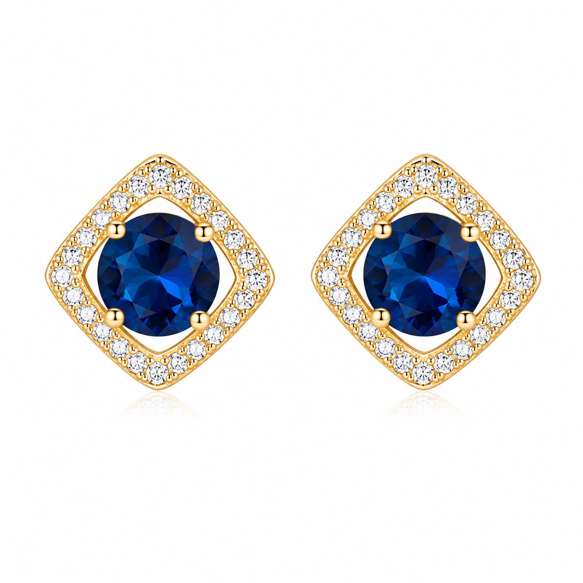 A pair of gold diamond-shaped stud earrings featuring a round deep blue center stone surrounded by a halo of small clear cubic zirconia stones, set against a plain white background.